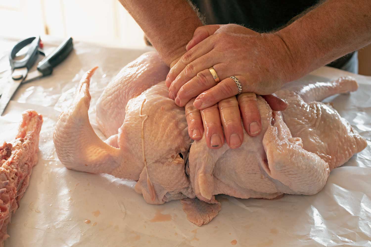 hands pressing turkey breast flat