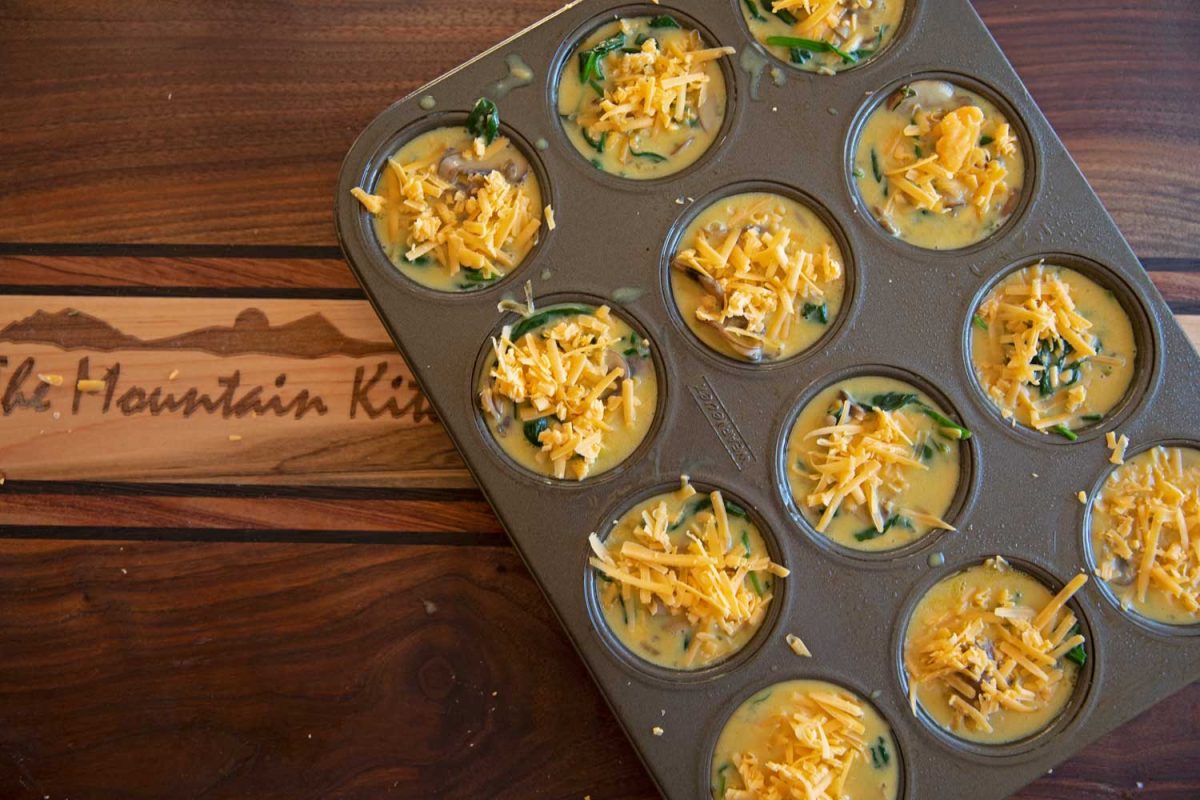 cheese topped quiche in muffin pan ready for oven