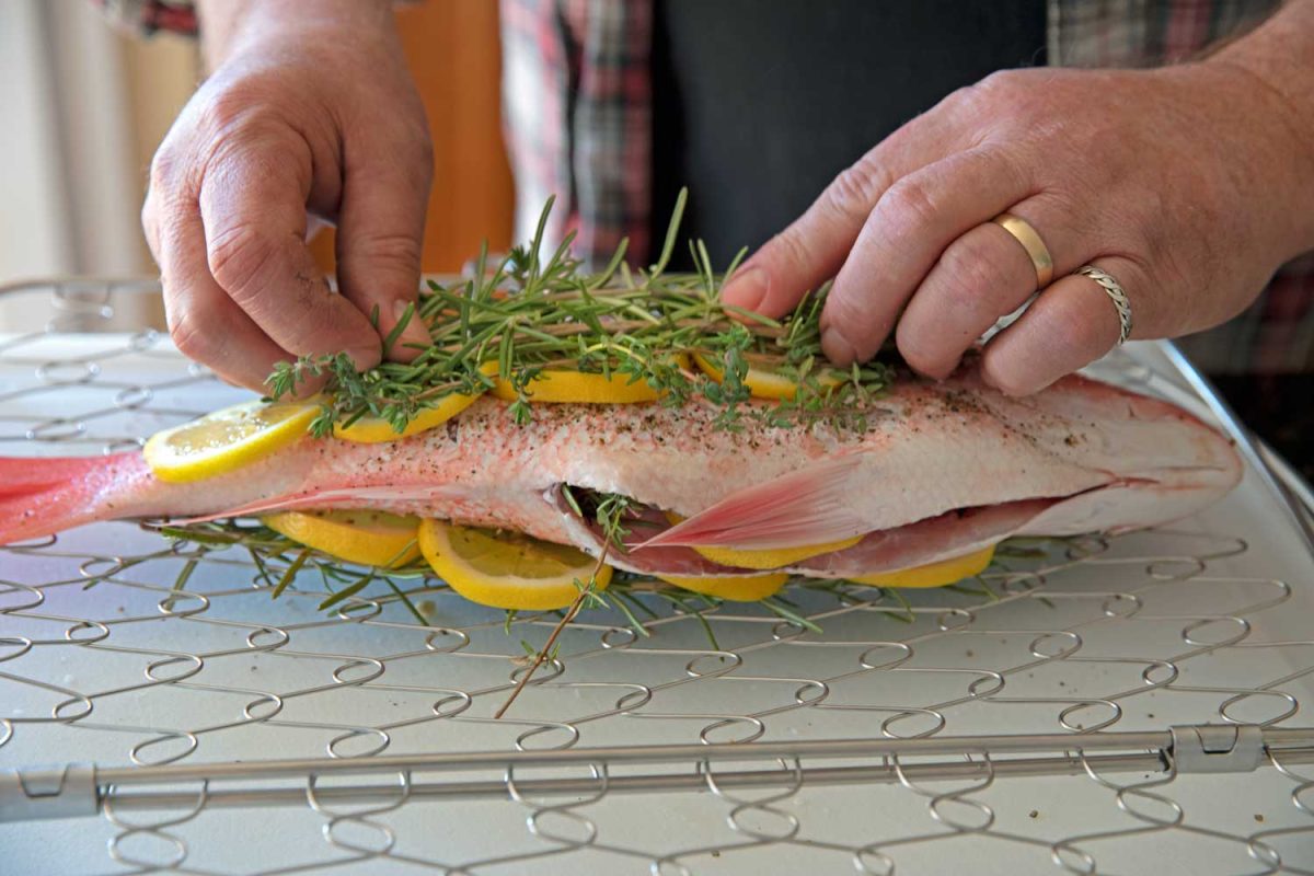 securing lemon slices and herbs on the fish