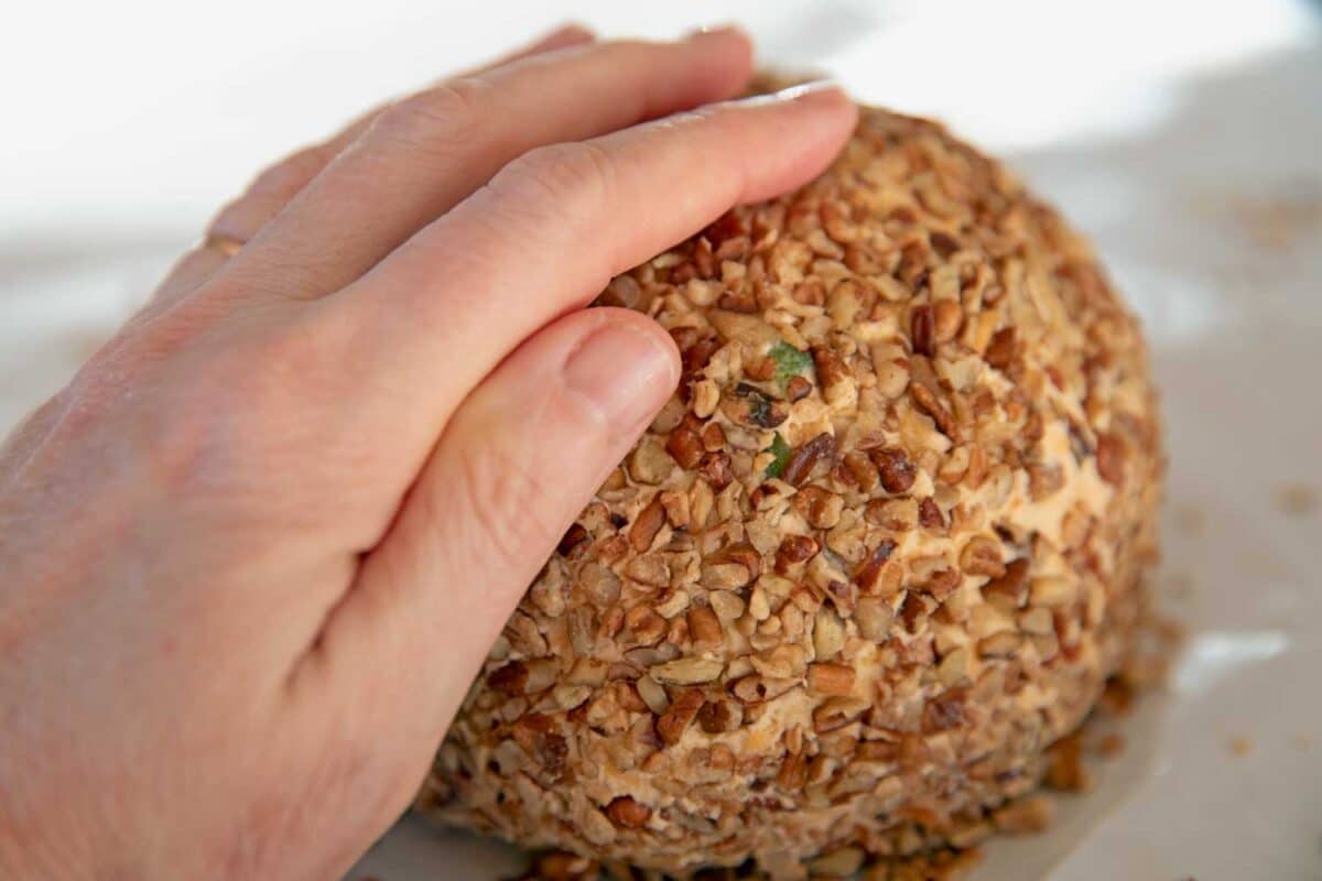 pressing pecans onto cheese ball