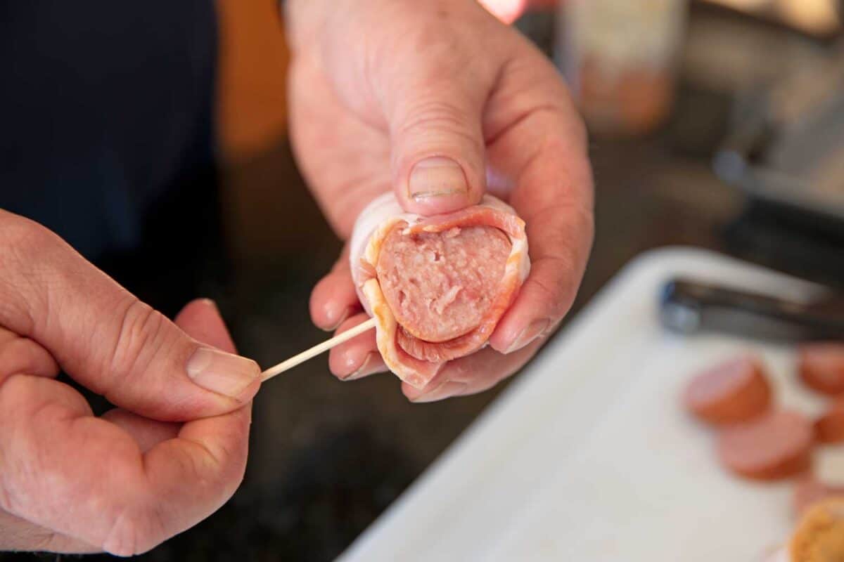 placing toothpick through bacon and sausage