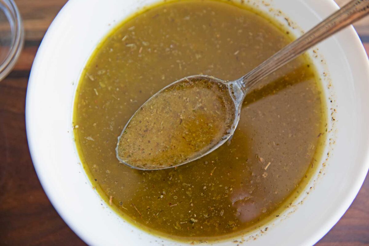 homemade greek salad dressing in bowl with spoon