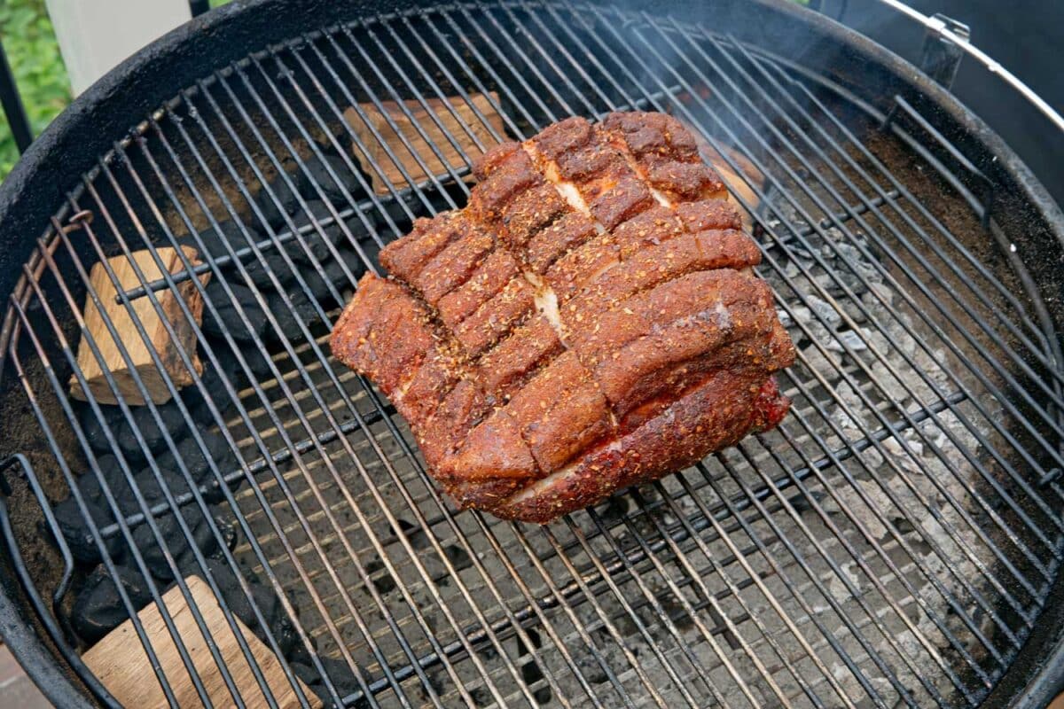 scored and rubbed pork butt on charcoal grill