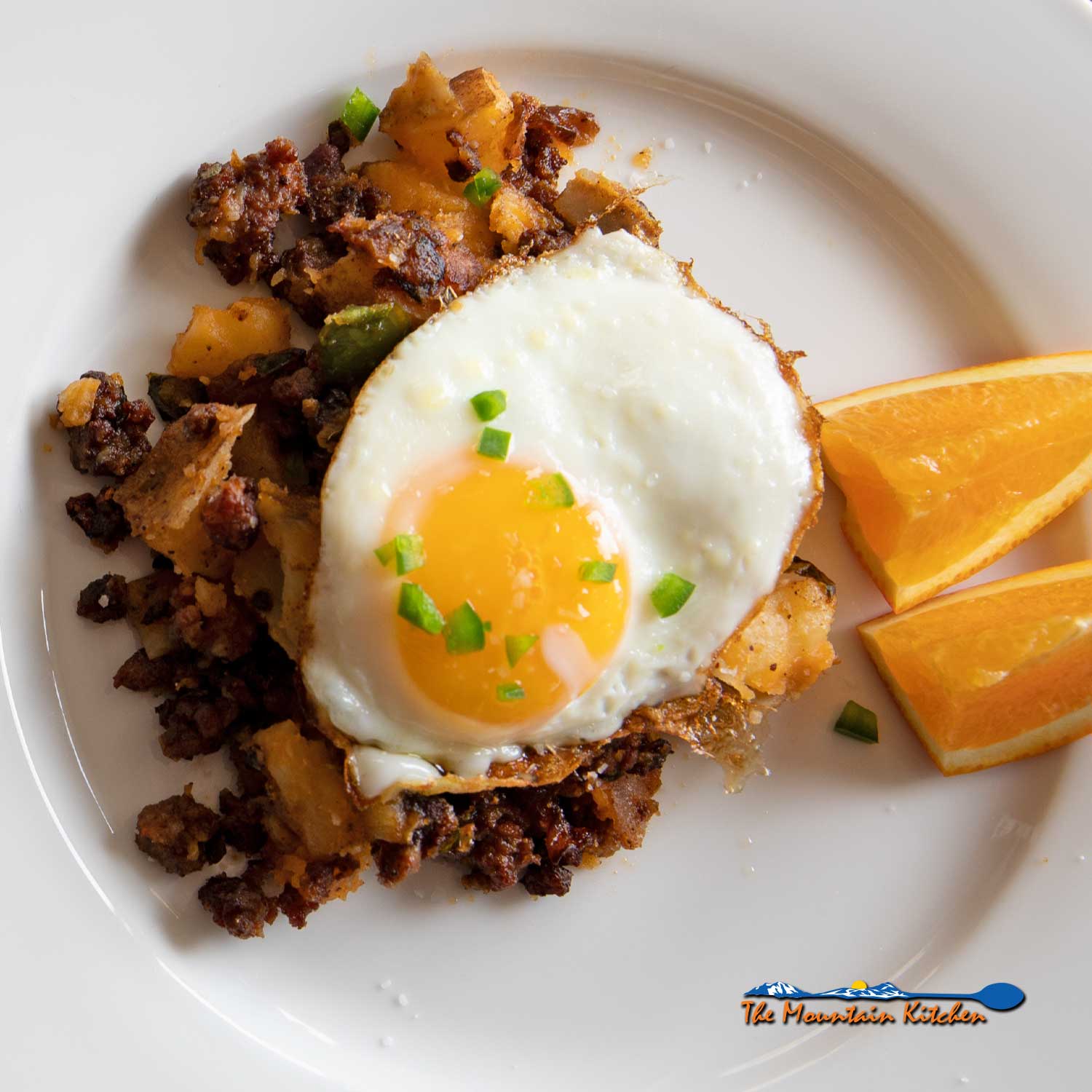 chorizo breakfast hash with fried egg and orange slices