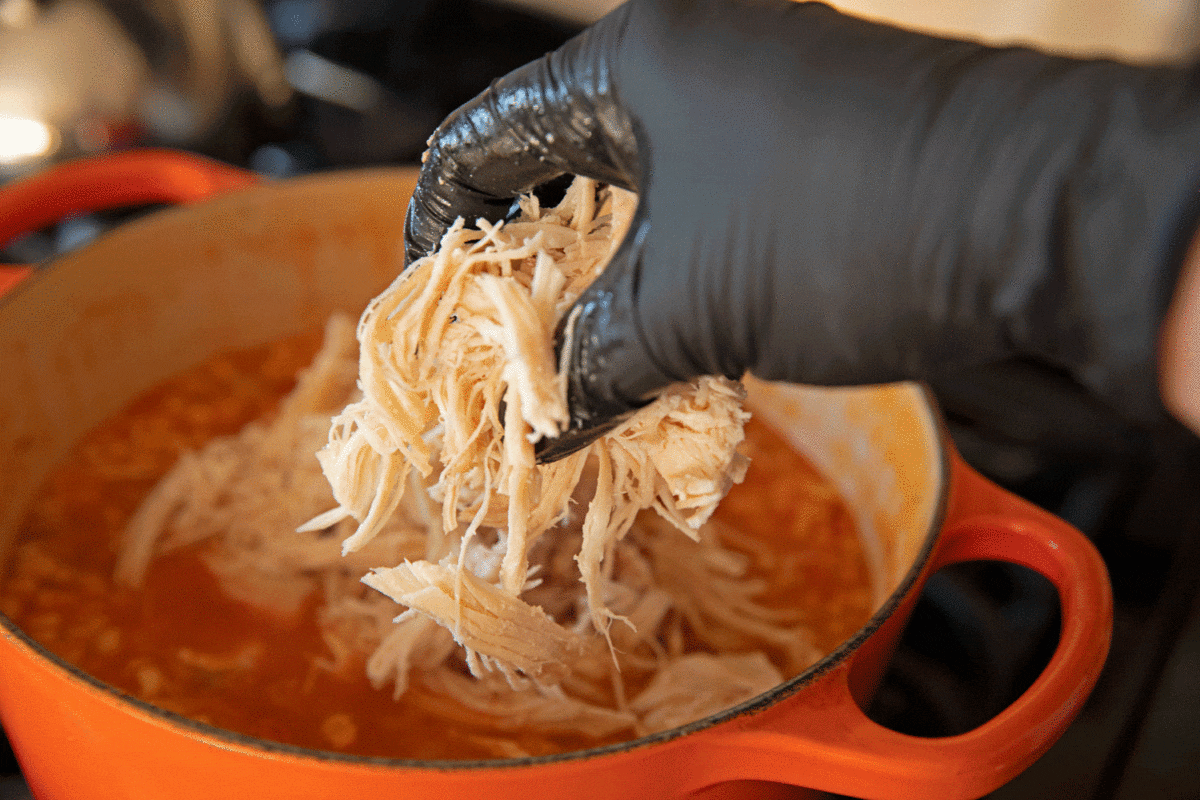 adding shredded chicken to the pot