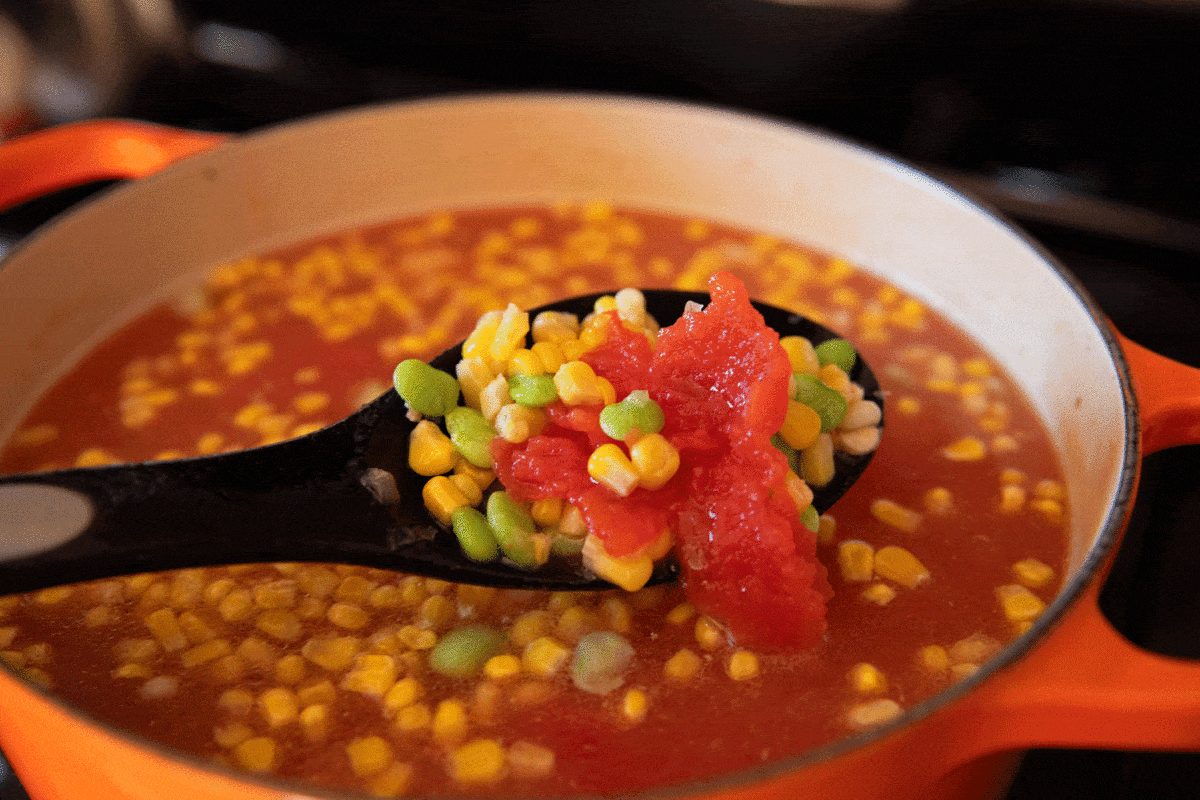 spoon of vegetables over soup pot