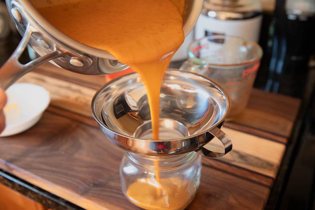 pouring chipotle cheese sauce into jar