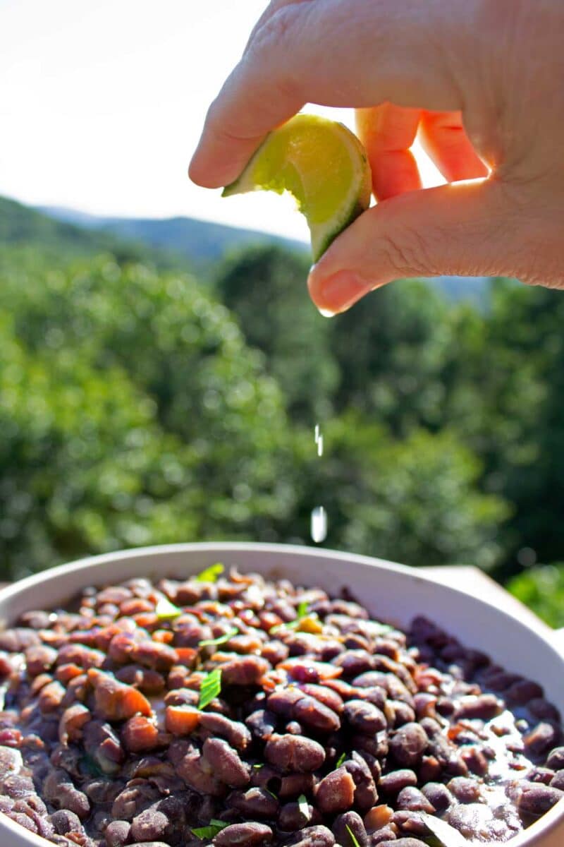 squeezing lime juice over bowl of cuban black beans