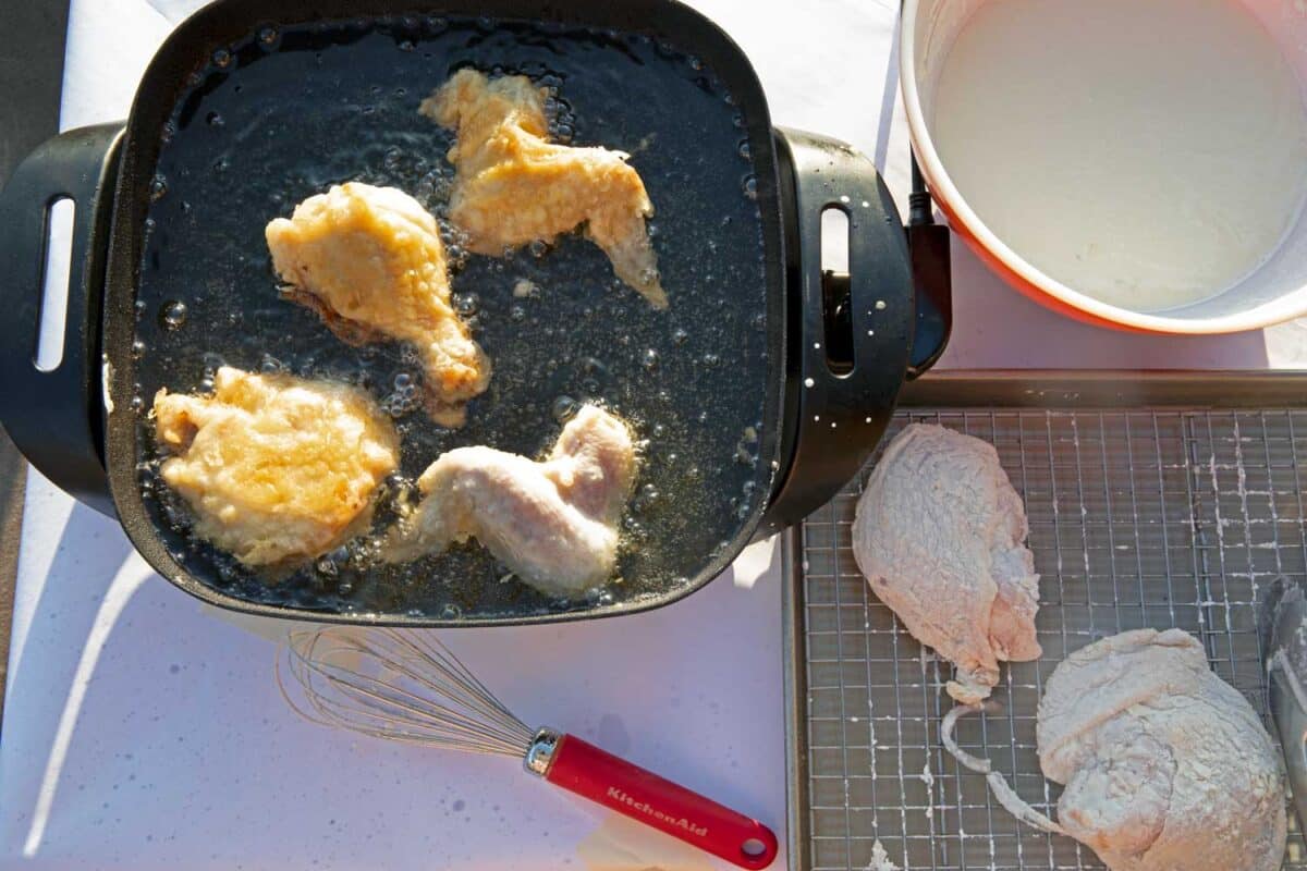 chicken frying with bowl of batter and battered chicken pieces