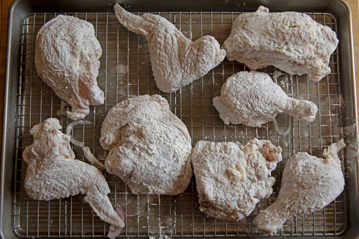 chicken pieces dredged in cornstarch coating on a wire rack